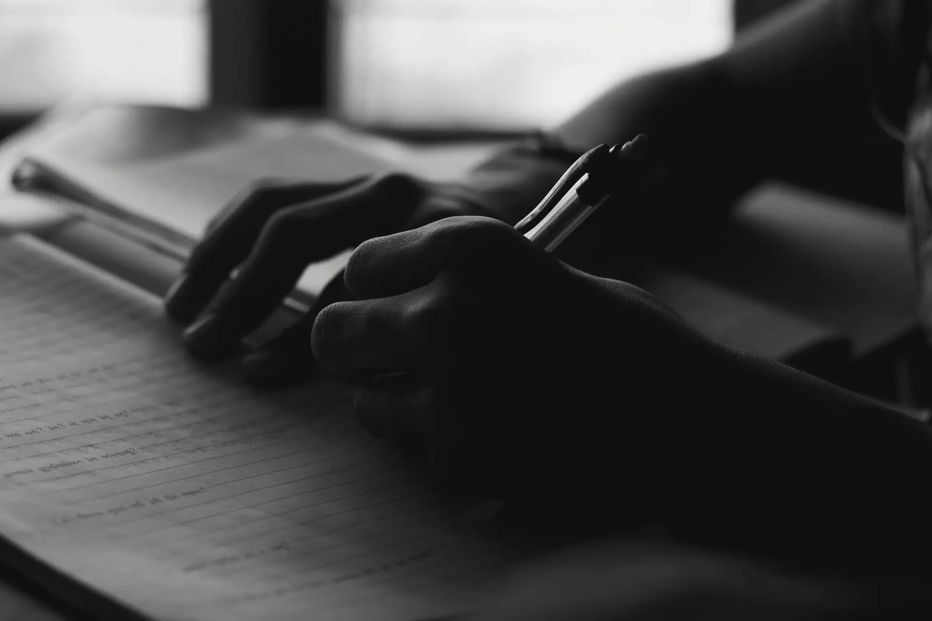 a person writing on a notebook with a pen